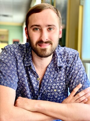 Grad student Patrick Kimutis smiles at the camera with crossed arms