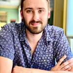 Grad student Patrick Kimutis smiles at the camera with crossed arms