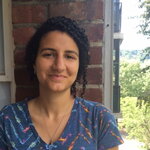 Grad Student Claire Baytaş stands outside against a brick wall and smiles at the camera.